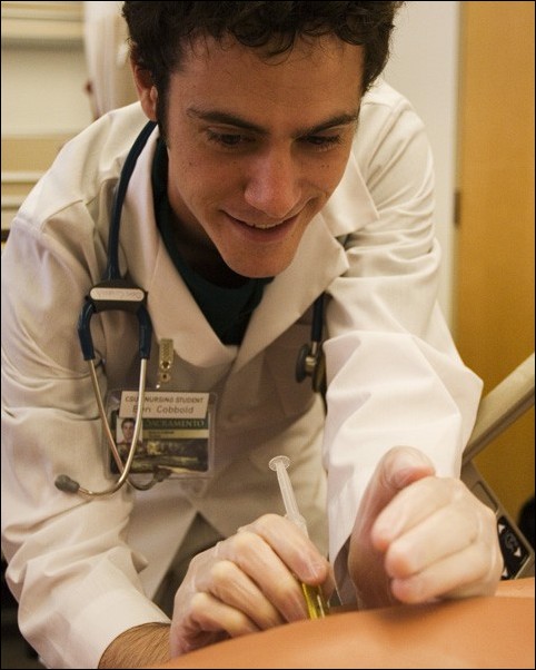 Image: Nursing department gets masters program:Student Ben Cobbold practices sticking a needle into a dummys arm in the El Dorado Hall nursing labs. Photo by: Nicholas Avey/ State Hornet:
