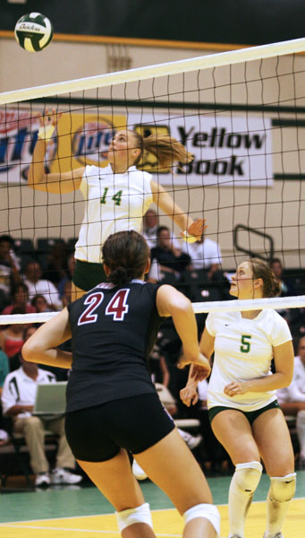 Senior Lindsay Haupt (left) spikes the ball past a Santa Clara player while teammate Rose Burke looks on.: