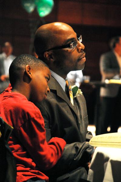 Former Sac State mens basketball coach Jerome Jenkins was honored Feb. 16 in the University Union. His son Jalen holds onto him as they listen to kind words spoken by the guest speakers.: