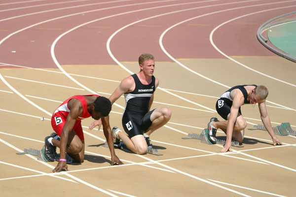 Sac State Sprinters David Houghton (4) and Derek Hammond (3) stretch at the blocks before a sprint.: