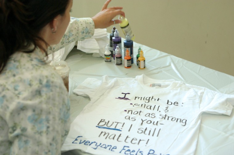 Junior social work major Crissy Goble decorates a t-shirt for women and children who have been victims of violence.: