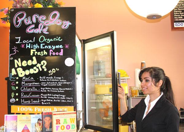 Nutritionist and Pure Joy Cafe employee Rebecca Wise helps a customer decide on which raw food item to order. Listed on the board are the boosts customers can add to smoothies.:Ashley Knight