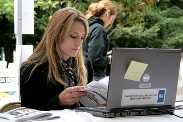 Senior business marketing major Amy Gallina reads through the voter brochure before she casts her votes for the ASI executive positions and the ballot measures.: