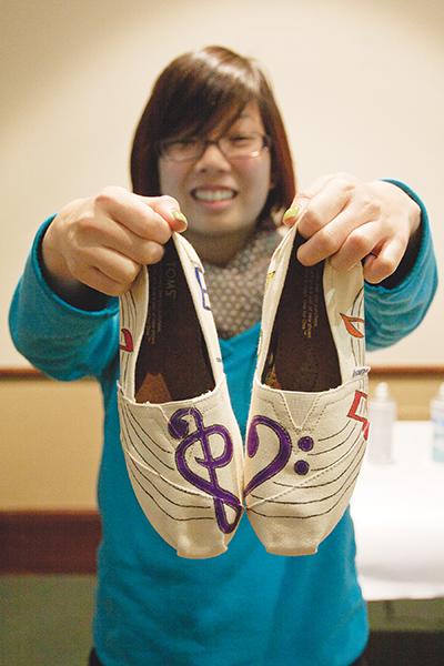 TOMS1:Christina L. Chun, avid violin player, shows off her new TOMS. Chun said she loves how the treble clef and bass clef make a heart and decided she wanted that design on her new shoes. Art supplies were supplied for students on Monday during Sac State?s TOMS Style Your Sole event in University Union Ballroom from noon to 4 p.m. TOMS are a charitable shoe manufacturer whose shoes cost $44. Each pair bought allows the organization to donate another pair of shoes to a child in need. :Brittany Bradley - State Hornet