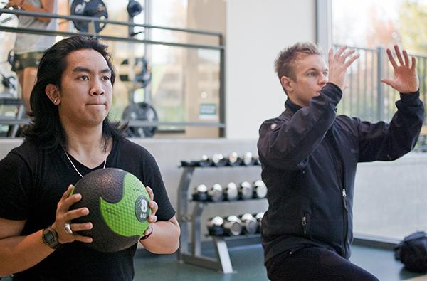 WELL personal trainers:Personal trainer Sam Brinkhuis, right, demonstrates medicine ball lifts with the help of a Well employee.:Robert Linggi - State Hornet