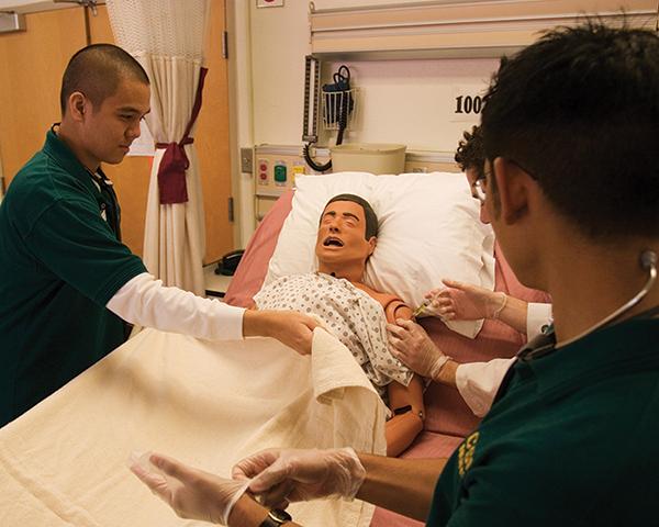 Nursing students practice on dummy:Estella, Cobbold and Romabiles help inject a test dummy patient. :File Photos