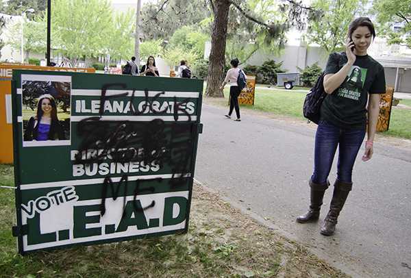 Ileana Grates, candidate for director of business, stands next to her graffitied campaign sign outside the University Library.