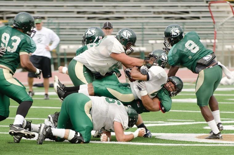 Junior running back Sam McCowan gets pulled down during Saturday’s green-gold game. The defensive team clearly held the upper hand during the game keeping the offensive to one touch down and a field goal while forcing four turnovers.