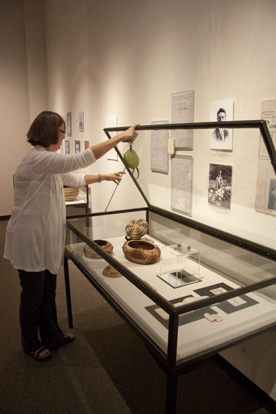 Terri Castaneda, director of the Anthropology Museum, opens up
the Pomo basket display for some of the visitors at the
exhibit. 
