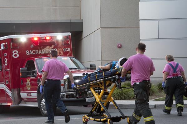 Paramedics wheel the victim to an ambulance. The woman was hit
on her bike by a car behind the Hornet Bookstore.
