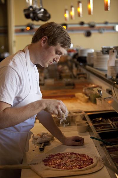 Employee Kameron Klima sprinkles cheese on a pizza after
hand-stretching homemade dough Oct. 11 at OneSpeed Pizza in East
Sacramento.
