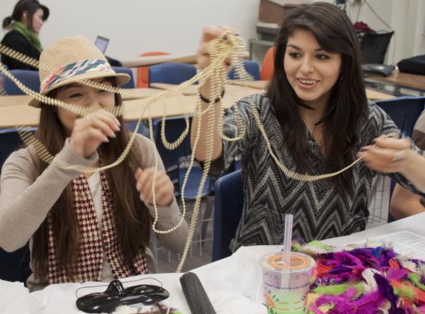 Nikki Khotpanya, senior apparel marketing and design major, and
Anai Vivanco, sophomore business major, use beads to decorate their
masks to sell at the upcoming fashion show.
