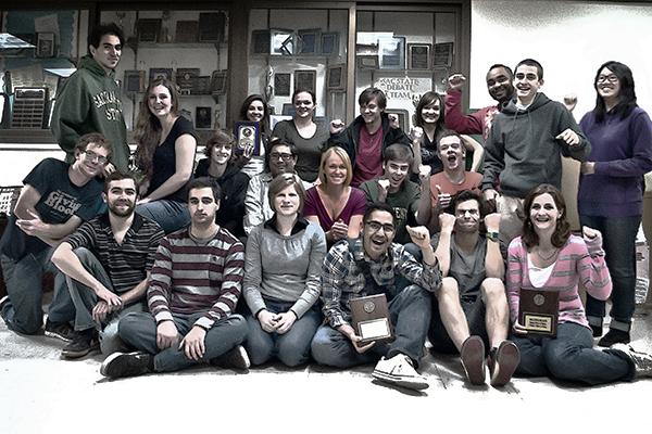 Members of Sac States debate team pose in front of their awards
- with Kristen Tudor, team coach, in the center 
