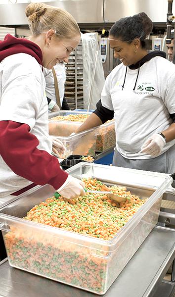 Anastasia Albrecht, criminal justice alumni (left), and
Alexandria White, senior biology major (right), share stories as
they fill up food trays. 
