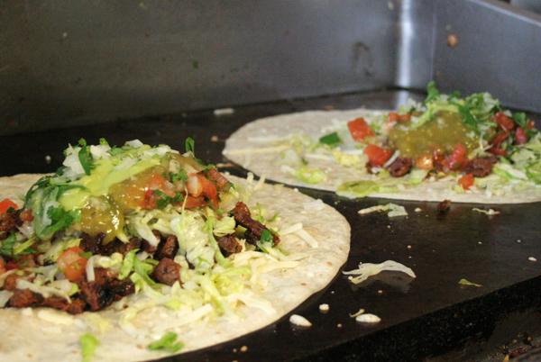 Burritos cook over a sizzling grill at Chando’s restaurant. 
