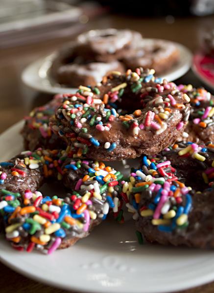 These gluten-free donuts are topped with chocolate glaze and sprinkles. 
