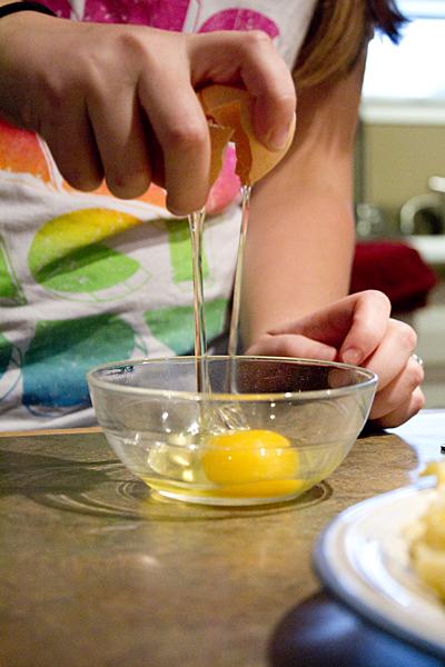 State Hornet Features writer Candice DeVries cracks open an egg to add into the cheese mixture for the lasagna. 
