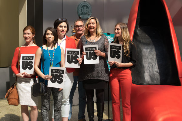 Staff pose with Its on us flyers representing the importance of Sexual Assault Awareness Month in the WELL, Monday, March 29.