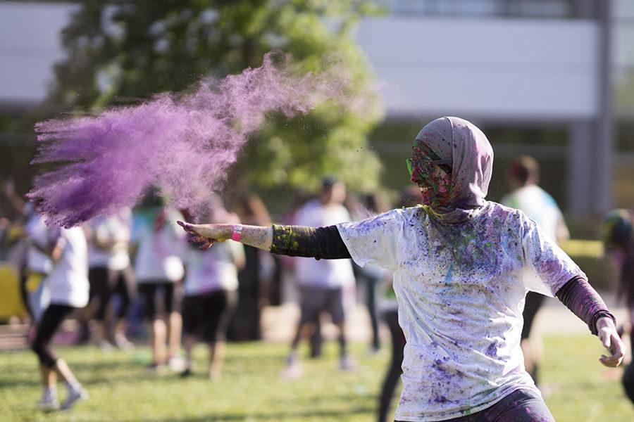 A Sacramento State student throws colorful powder during the Hornet Holi event hosted by Bhagat Puran Singh Health Initiative (BPSHI) in the Well front lawn, Friday, April 29.