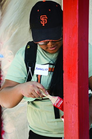 Senior Angelica Manganay paints the trim of a house red in Oak Park, on Saturday, Sept. 17. (Photo by Matt Dyer)