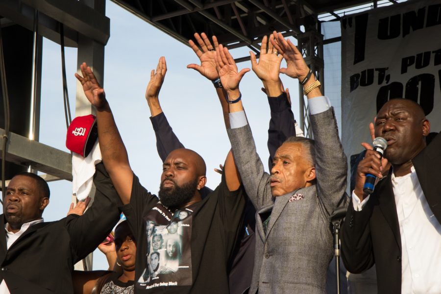 Michael Brown Sr., second from left, with Rev. Al Sharpton, second from right, as Attorney Benjamin Crump leads a call and response of Hands up, dont shoot, at the St. Louis Peace Fest. Brown will be appearing at Sacramento State on Oct. 20. (Photo by Brett Myers/Youth Radio)
