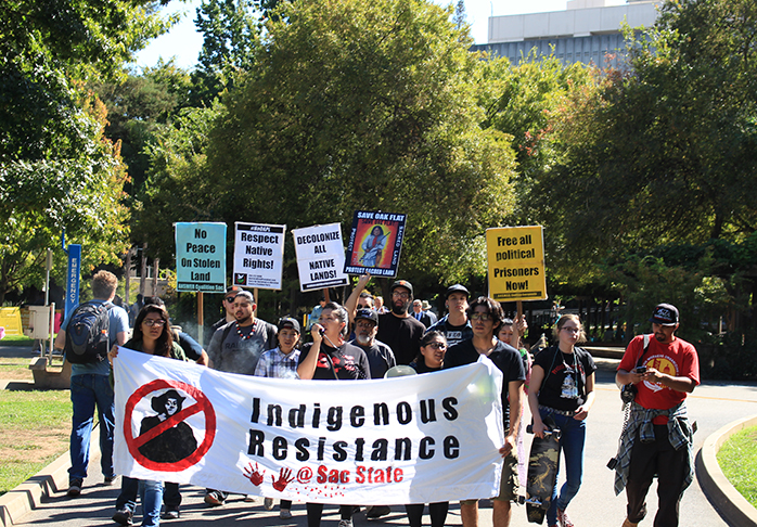 Students march from the library quad to the administration building protesting the continued celebration of Columbus Day on Monday, Oct. 10, 2016. Denise Fernandez, pictured in the middle with the megaphone, said that she helped organize the march to draw attention to issues affecting the Native American community (Photo by John Ferrannini).