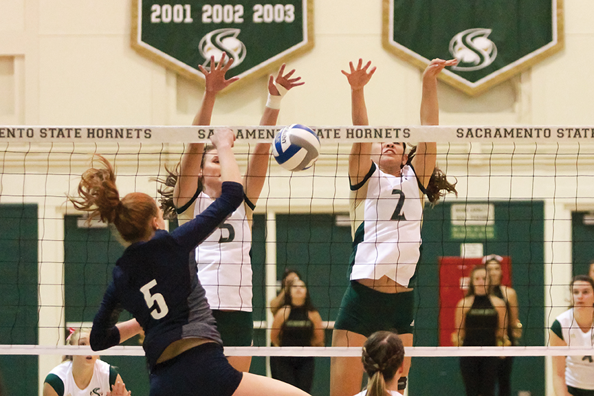 Sacramento State senior blockers Courtney Dietrich and Madeline Cannon block the ball from Lauren Jacobsen of Northern Arizona at Colberg Court on Oct. 27. (Photo by Matthew Dyer)