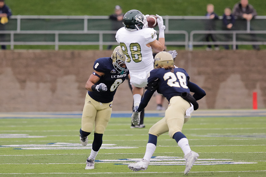 Sacramento State sophomore tight end John McGill leaps for the ball between two UC Davis defenders at Aggie Stadium on Saturday, Nov. 19. (Photo by Matthew Dyer)