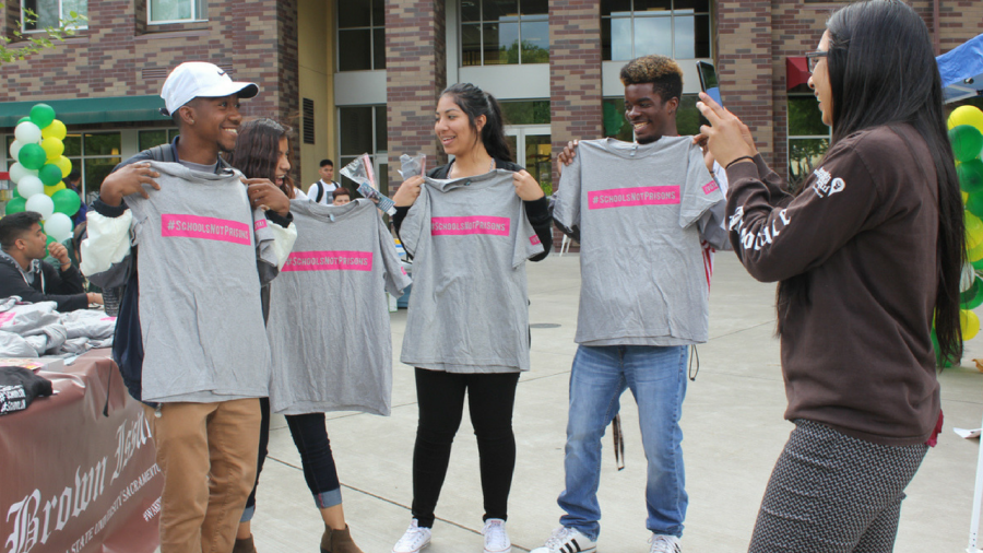 From left to right, Sacramento State freshmen Demeturius Turner, Reyna Flores, Lizett Mendez and Antione Phillips hold up the T-shirts they received during the Multicultural Fair on April 26 at the Residence Hall Quad. (Photo by Myha Sanderford)