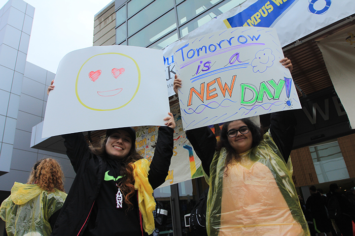 Students Isabel Chavarria, left, and Grace Soria hold signs they made for the Out of the Darkness walk. (Photo by Ricardo Coronado)