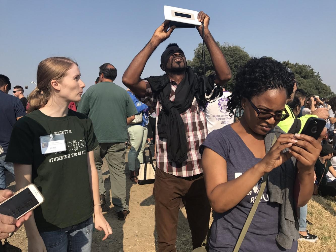 Physics student and volunteer Leah Weston help attendees use the welding lens at the solar eclipse viewing party at the American River levee across from Hornet Bookstore on Monday.