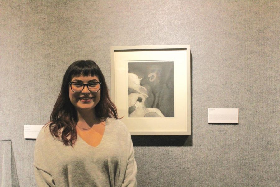 Junior art history major Janina Lopez poses with the painting of her choice in the exhibit. For the exhibit, students were responsible for selecting, researching and writing about a piece from the Art Department Collection. 