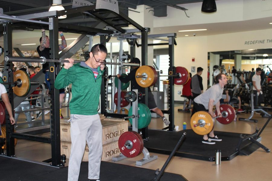 Sacramento State senior business administration major Willy Hoang, left, warms up with a barbell as he prepares for a squat session with the Sacramento State Stinger Barbell Club at The WELL.