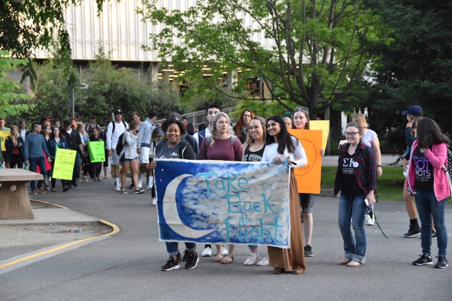 Bajha Jordan, left, with banner, the student manager of Health and Wellness Promotion, leads a crowd of students across campus. The Healthy Relationships program at Sac State held a Take Back the Night march on Thursday, April 26.