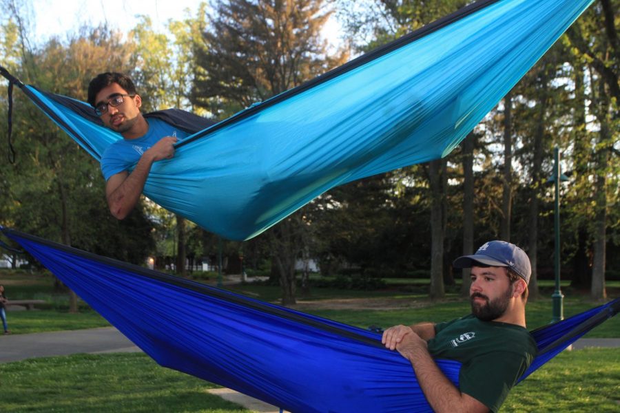 Computer science major Armaiz Adenwala, top, and business finance major and Hammock Club President Trent Simonson, bottom, engage with other members of Hammock Club at a Monday evening meeting on April 2, 2018 in grouping of trees between Riverfront Center, Lassen Hall and the bus stop. Hammock Club meetings are held Monday and Thursday evenings, and are open to all students.