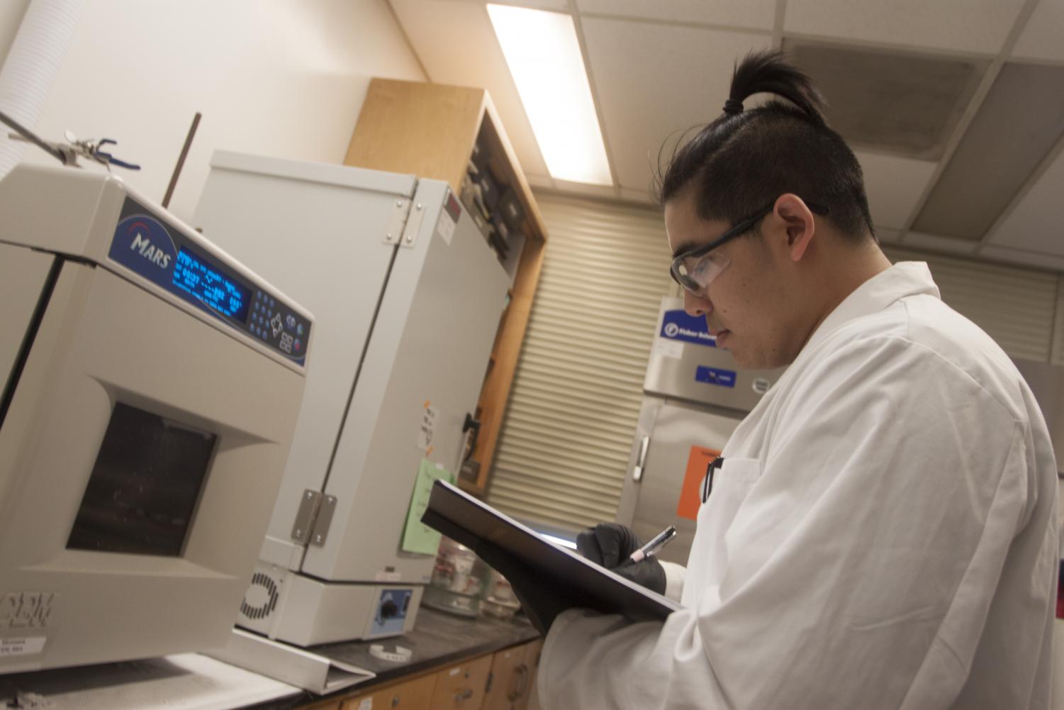 Biochemistry major Kevin Tran uses the microwave in a laboratory on the fifth floor of Sequoia Hall on April 19, 2018 to break down molecules. Tran is working with professor Katherine McReynolds on a project that may yield a topical medicine aimed at preventing the spread of HIV.