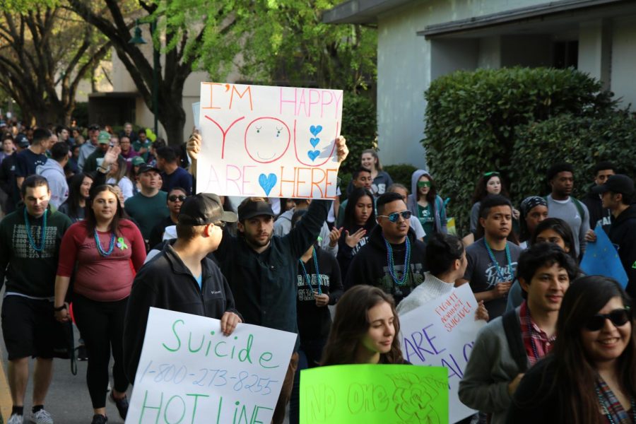 Participants of the Out of the Darkness Walk hold signs as they walk to the residence halls on April 12, 2018. This years event aims to raise $22,000 for suicide prevention. 