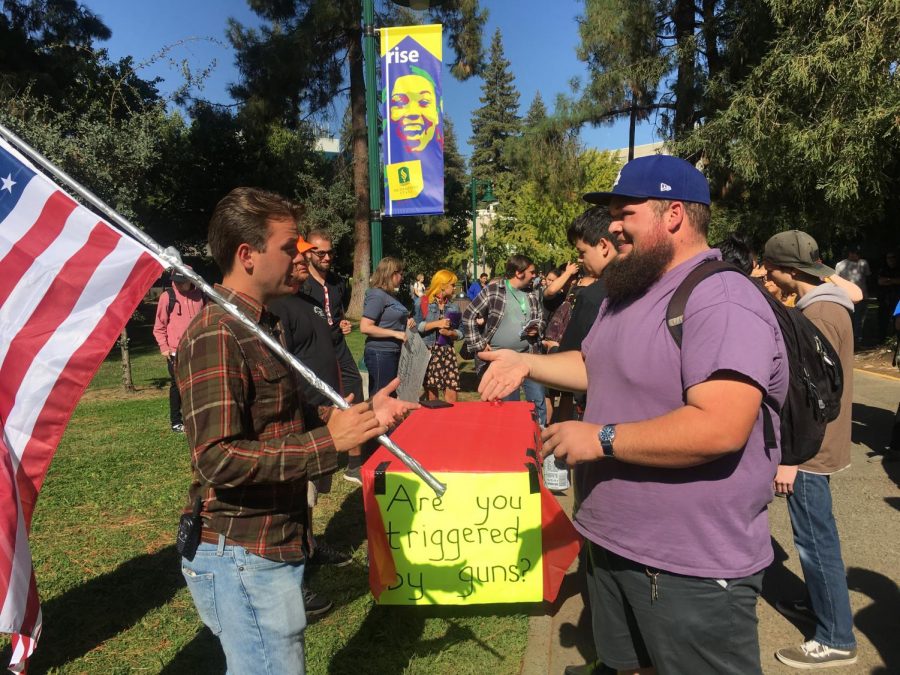 Students attempt to have a more peaceful debate about gun rights amid a shouting match outside the Library Quad Thursday. The booth from Students For Self-Defense attracted a crowd after a shouting match erupted between two veterans.