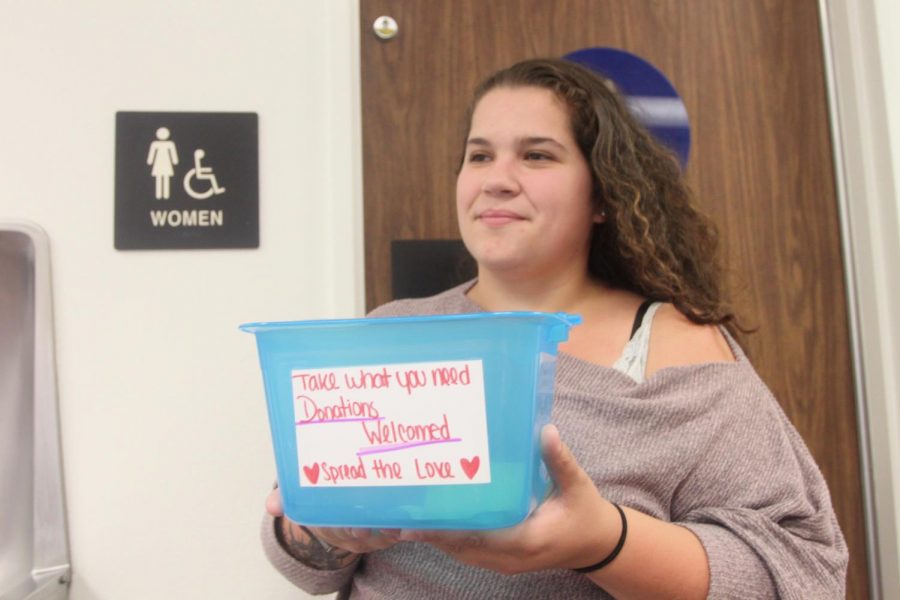 Ethnic studies major Elizabeth Winn holds a box containing free menstrual products outside of a fourth floor bathroom in the Library. Winn and child development major Cassandra Lopez started Mother Natures Gift together.