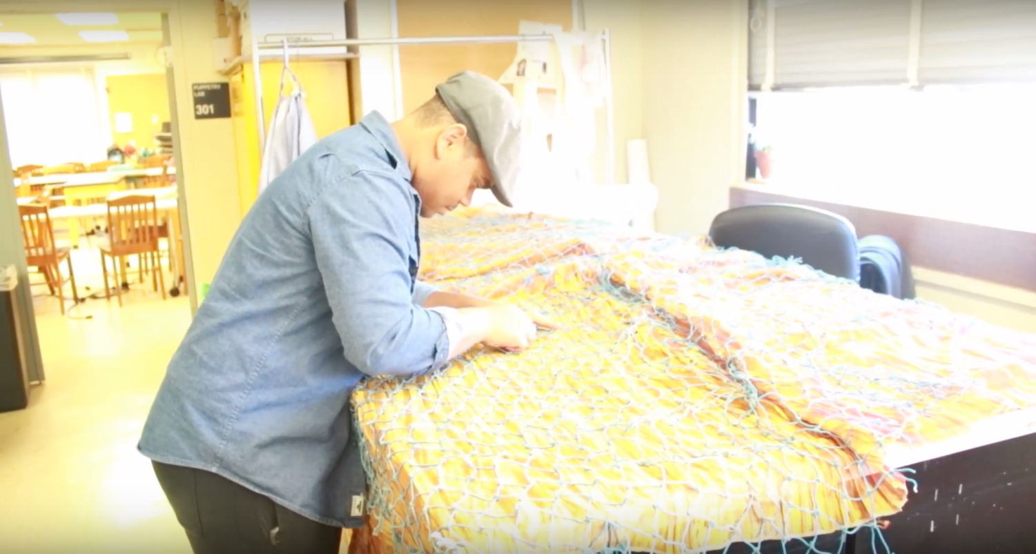 Costume assistant, Miles Meckling, works on sewing cord together to create a river to be used on stage. This river is part of a set design for 'Peter and the Starcatcher' that includes a stage painted entirely by hand.