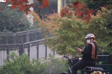 A female biker stops in front of the Sacramento State library to take photos of the smoke-filled closed campus on Nov. 14. 