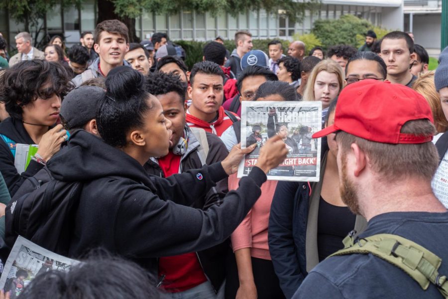 Taryn Patton points at a copy of the State Hornet in a crowd of people in the Library Quad Thursday. A fight broke out at Sac State after a group of men wearing Make America Great Again hats with a Blue Lives Matter flag accused The State Hornet of inciting violence in its latest print issue.