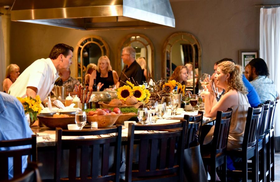 The Kitchen guests enjoy dinner and glass of wine at the counter surrounding the chefs, who cook and prepare their meals right in front of them.