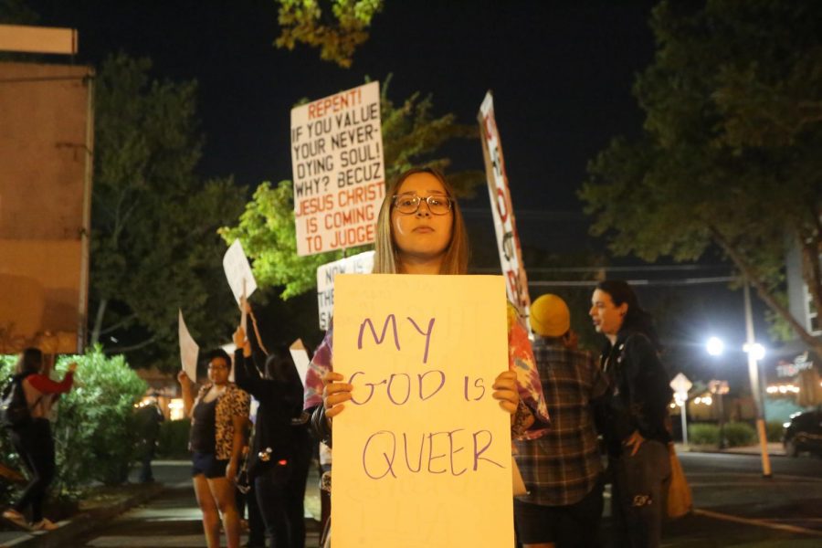 Emigh Turnbull, an El Camino High School junior, holds up a sign in front of protesters at the Take Back the Night rally and march Saturday evening. Growing up Christian, I know he is all loving and to not accept others for who they are is not Gods way, she said. 