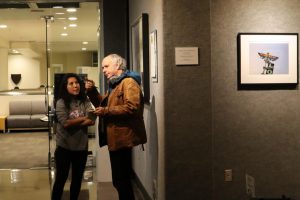 First-year Sac State student Alex Sengbounouvong discusses René Domingos photographs with another visitor at the opening reception of her Neon and Nostalgia exhibit Thursday. The exhibit will last until Feb. 13. 