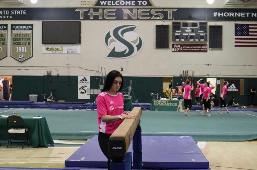 Mariah York poses next to the balance beam before a meet with Alaska Anchorage at the Nest on Sunday, Feb. 16. York has been battling injuries her whole collegiate career and will be out for her entire junior year following ankle surgery.