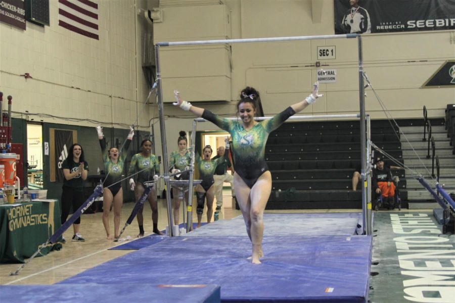 Sac State sophomore Amber Koeth strikes a pose after finishing her routine on the bars Friday, Feb. 28 as her teammates cheer her on in the background at the Nest. The team hopes to place higher at MPSF Championships after placing fifth last season.