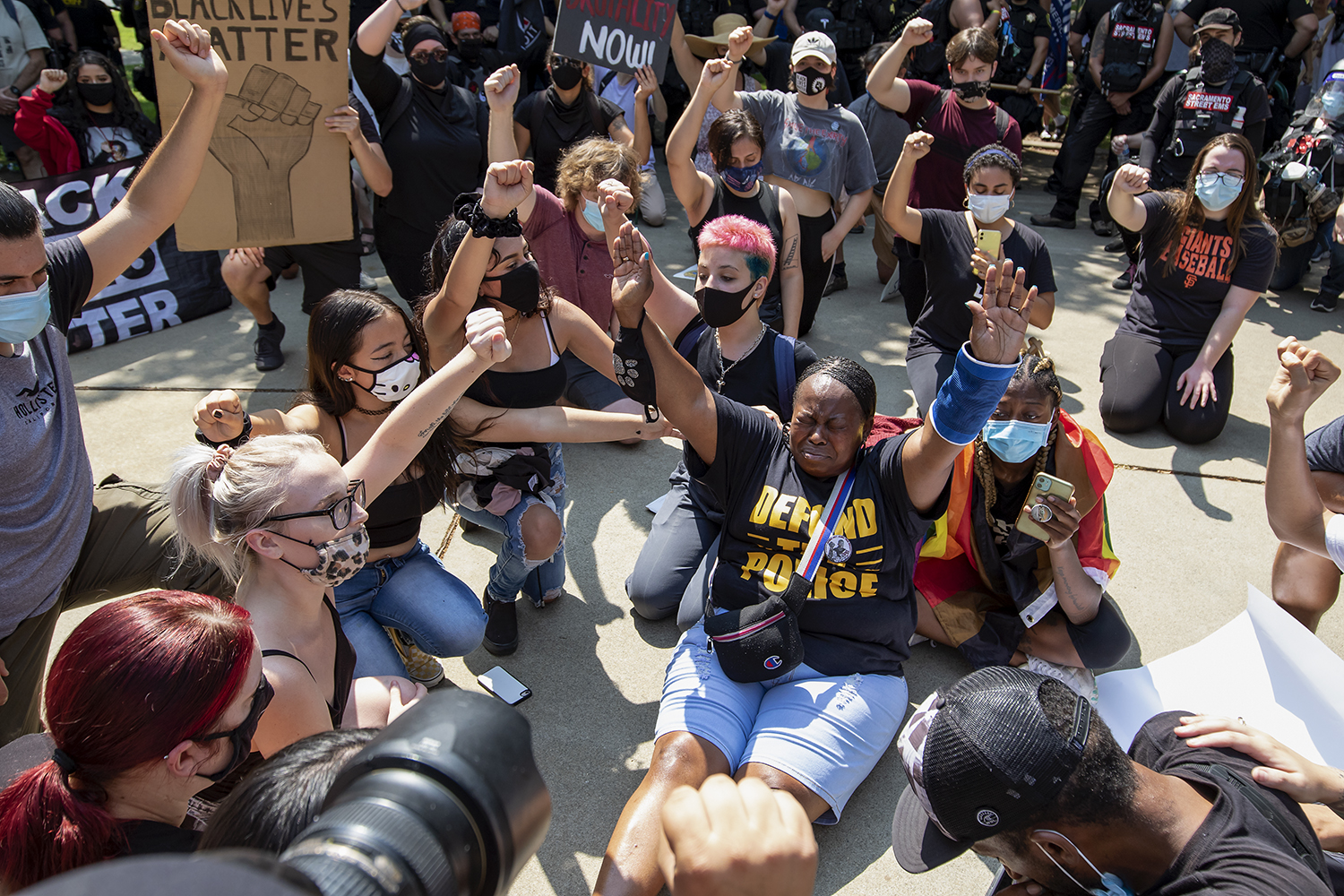 Dionne Smith-Downs, right, of Stockton sits and raises her arms during a Defund the Lodi PD rally in Lodi, California, Saturday, Sept. 5, 2020. Her 16-year-old son James Rivera was shot and killed by a Stockton PD officer. 
