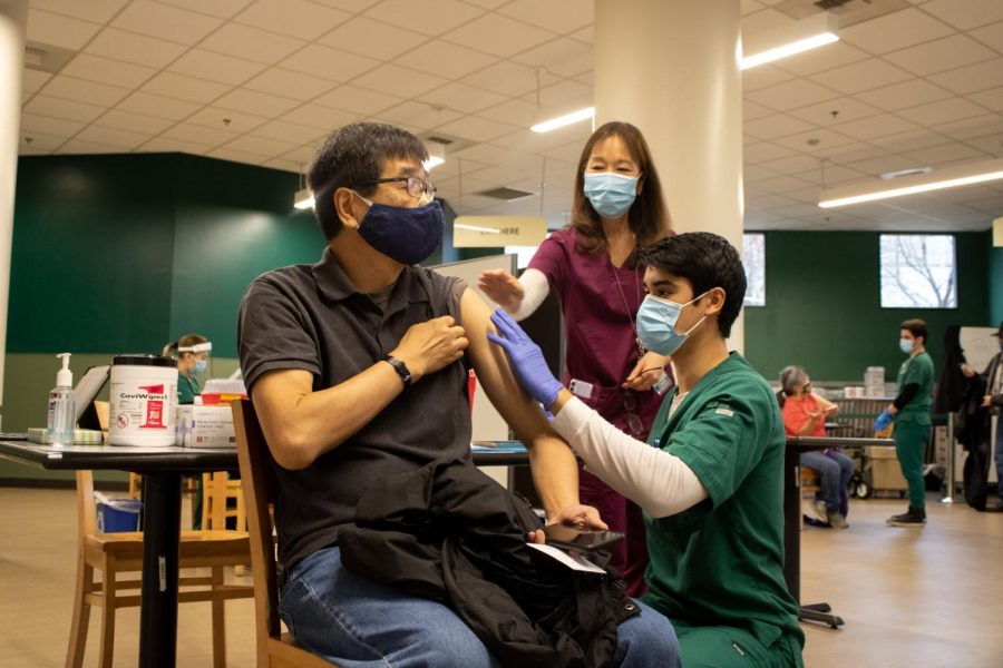 Francis Yuen, faculty in social work, gets injected with his first dose of the COVID-19 vaccine by Austin Friedheim on Jan. 28, 2021 in the Brown Bag room in the Union. 88 Sacramento State students are not in compliance with the university’s COVID-19 vaccination certification policy, according to President Robert Nelsen. 