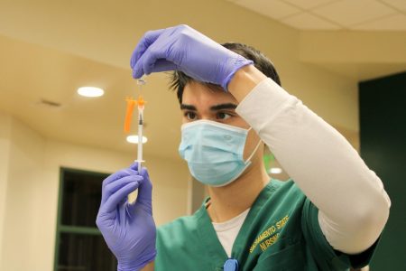 (File photo) Austin Friedheim, nursing student at Sacramento State, fills the needle up with the COVID-19 vaccine to inject patients in the Brown Bag room in the Union on Thursday, Jan. 28, 2021. The California State University system will require faculty, staff and students who will be accessing campus facilities in fall 2021 to receive the COVID-19 vaccination after the Food and Drug administration gives approval, according to an email announcement by the CSU on Thursday.